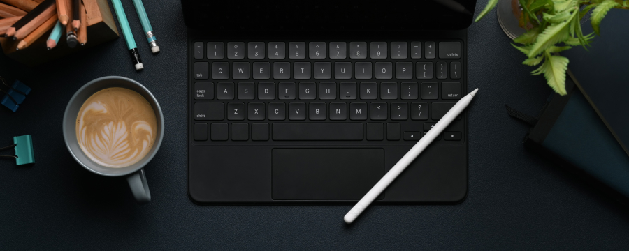 Coffee next to an iPad keyboard in a dark setting